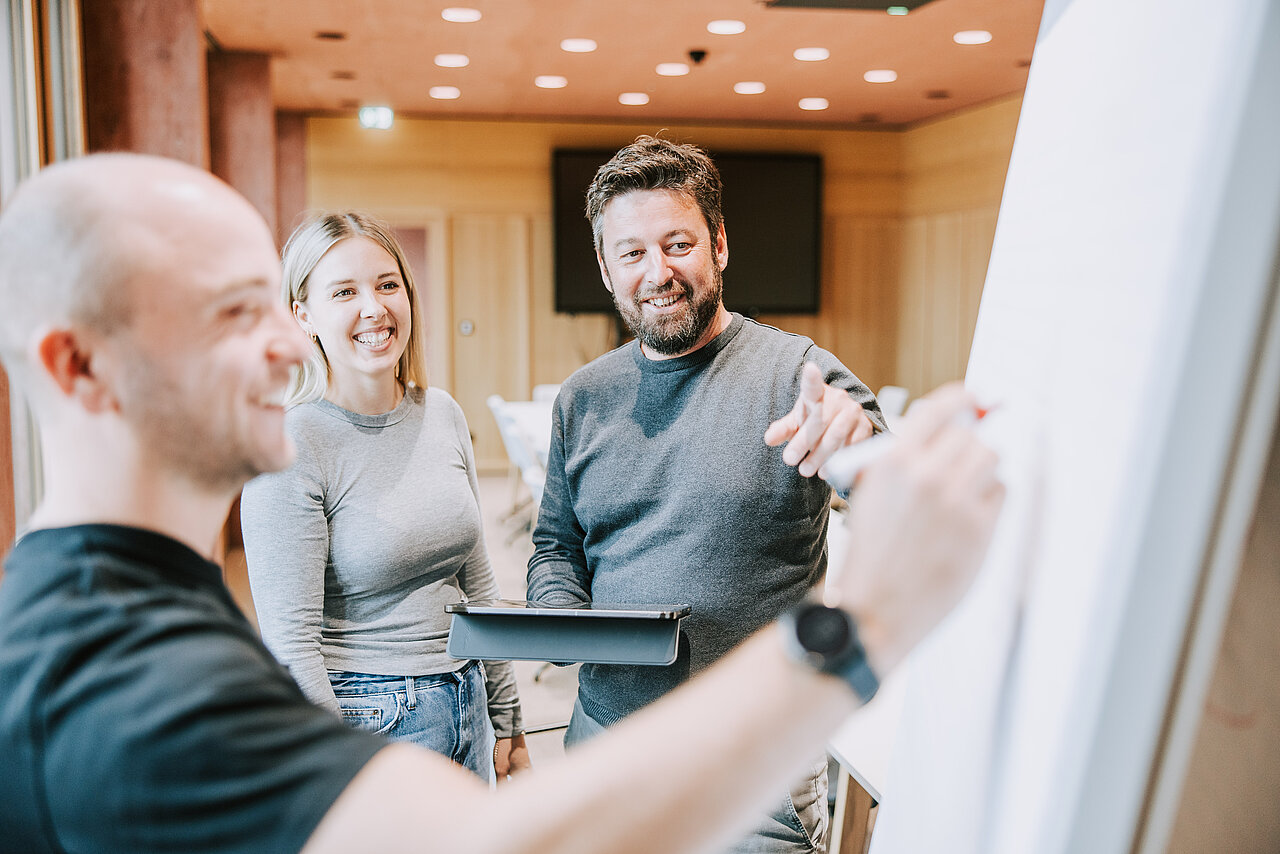 Drei Jäger Bau Mitarbeiter besprechen gemeinsam mit Flipchart und Tablet