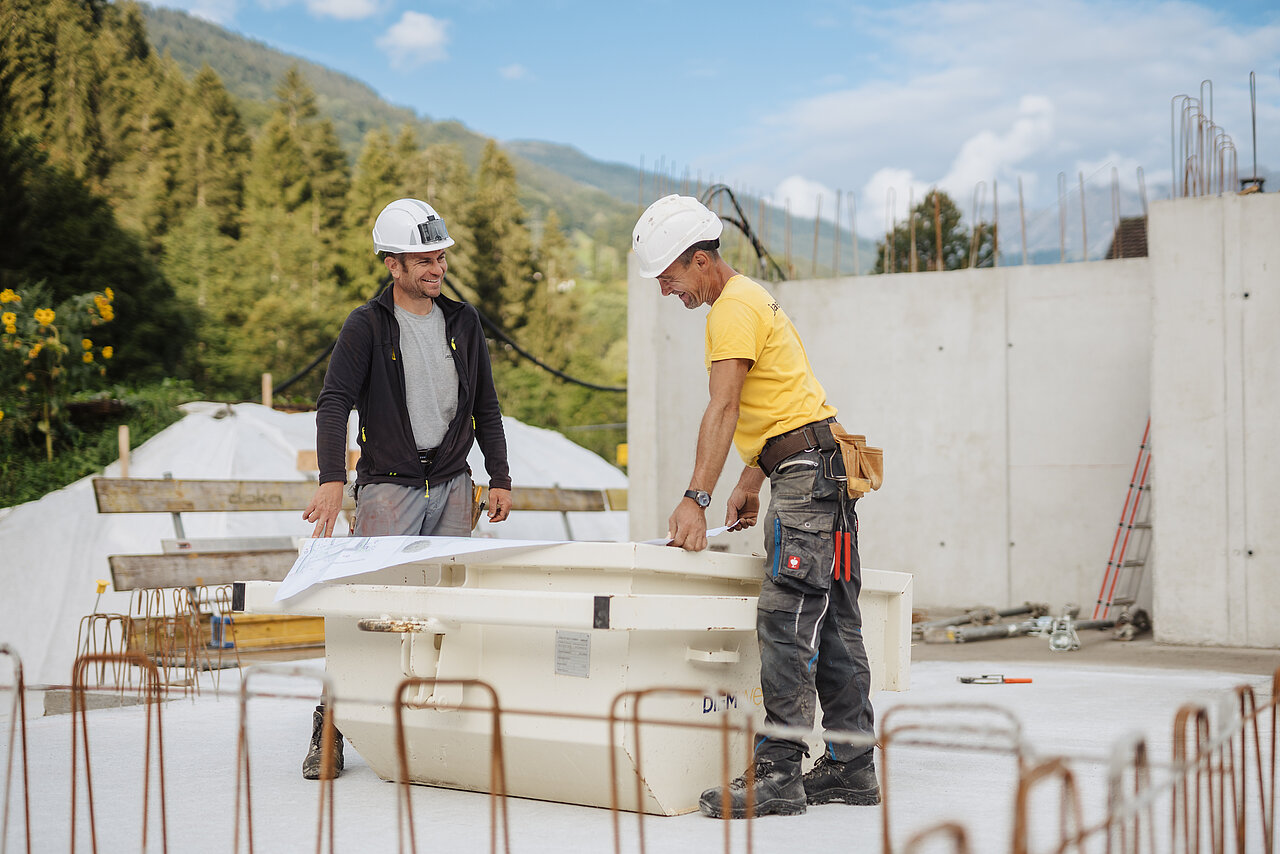 Zwei Jäger Bau Mitarbeiter betrachten einen Plan auf der Baustelle