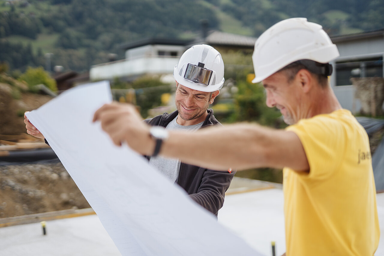 Zwei Jäger Bau Mitarbeiter betrachten einen Plan auf der Baustelle