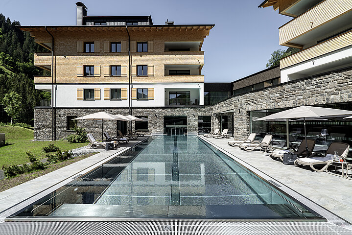 Arlberg Resort Klösterle Pool mit Resort im Hintergrund im Sommer
