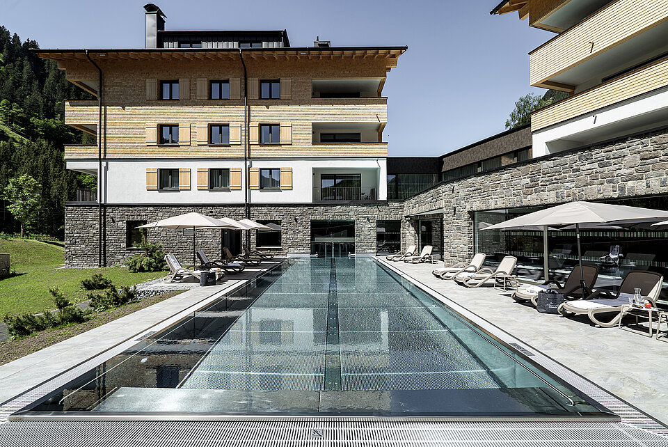 Arlberg Resort Klösterle Pool mit Resort im Hintergrund im Sommer